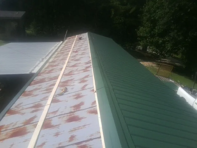 Old rusted panels beside newly installed green metal roofing — Wind Damage Roof Repair by Roofing Brothers in East Moriches