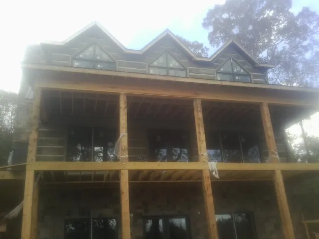 Dormers and porch framing on a large log home under construction — Roof Coating work by our crew in East Moriches