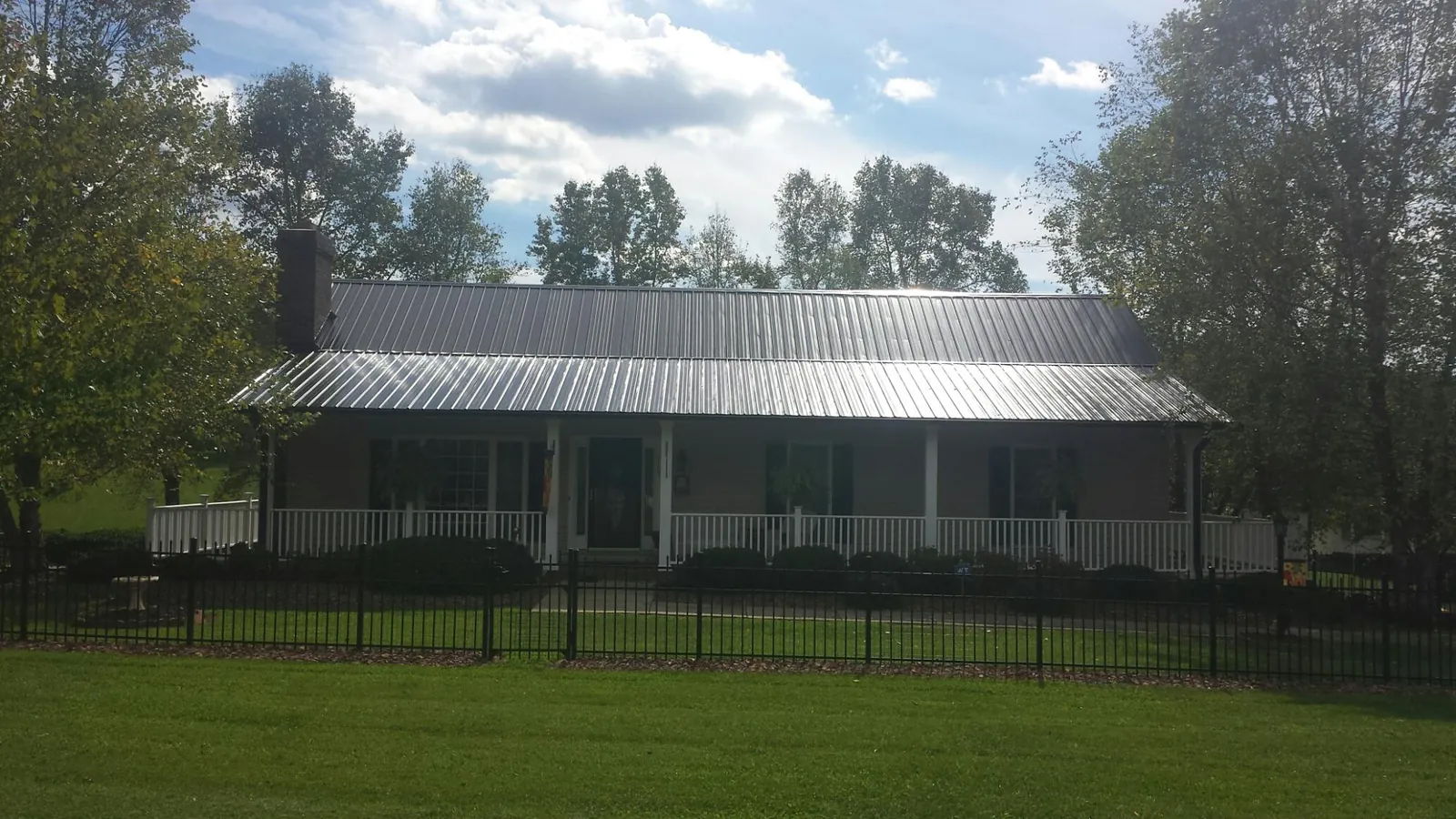 Gray metal roof on a brick ranch with a full width front porch — Gutter Guard Installation work by our crew in East Moriches