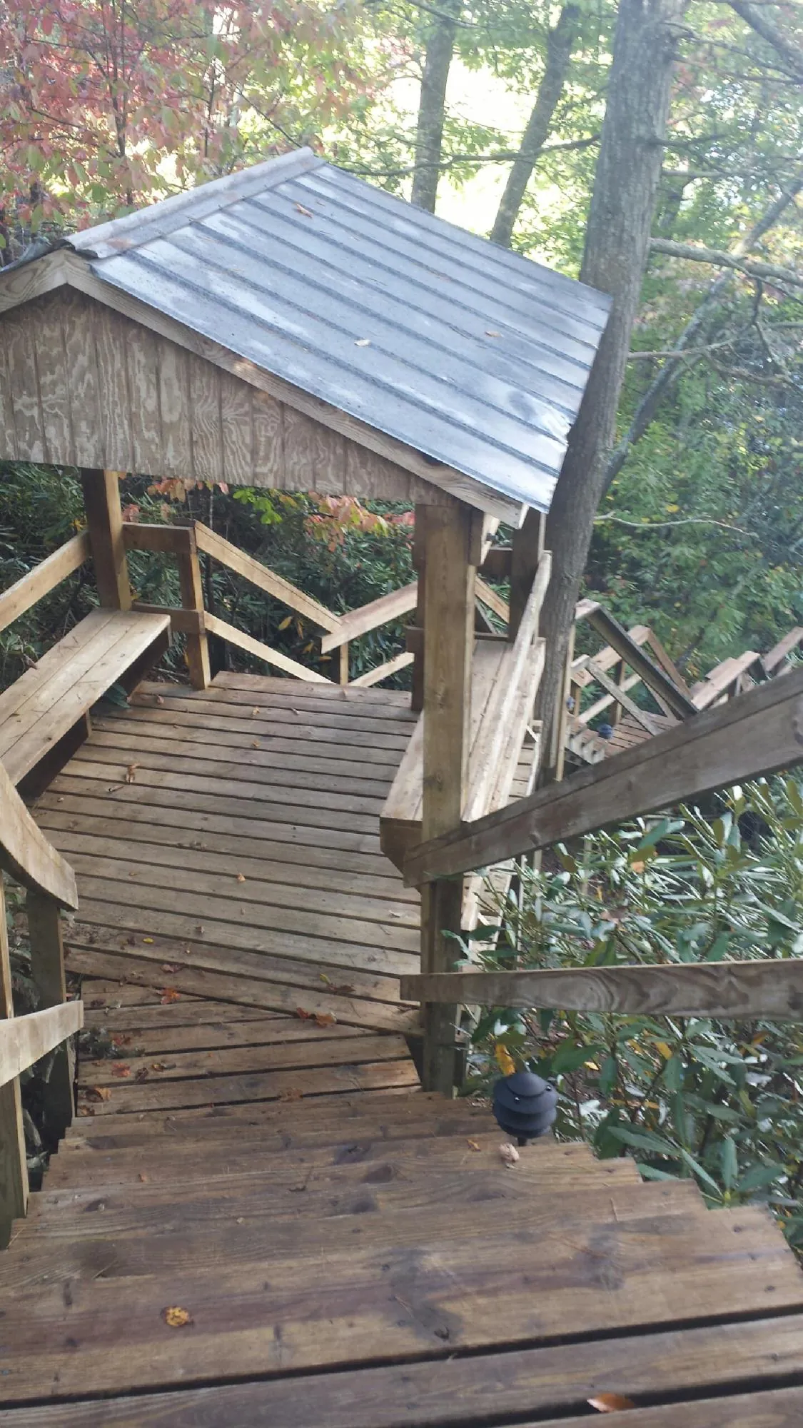 Metal roofed shelter over wooden steps on a wooded walkway — Skylight Repair & Installation work by our crew in East Moriches