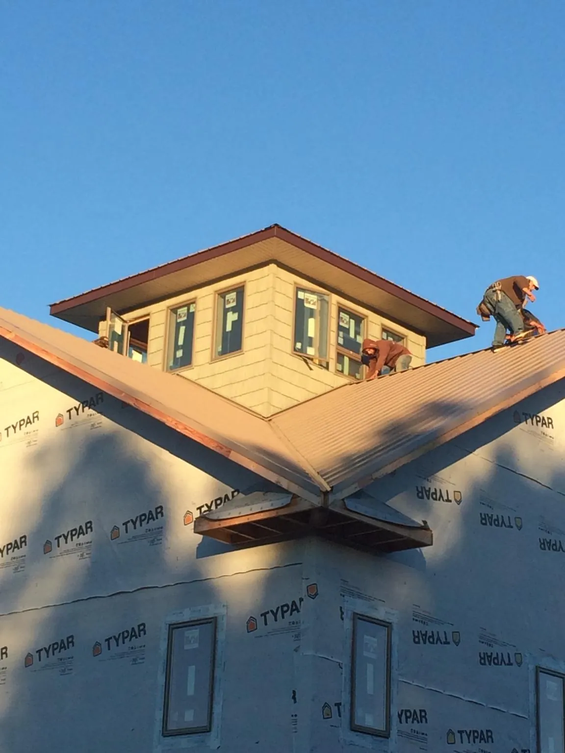 Roofers working around a rooftop cupola on a new metal roof at sunset — Roof Waterproofing in East Moriches by Roofing Brothers